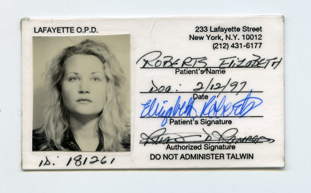 A black and white photo ID of a fem presenting person staring into the camera with no smile. On the right, written name "Roberts Elizabeth" in Patient field, signatures and birthdate with a New York address in black typed text at the top right corner.