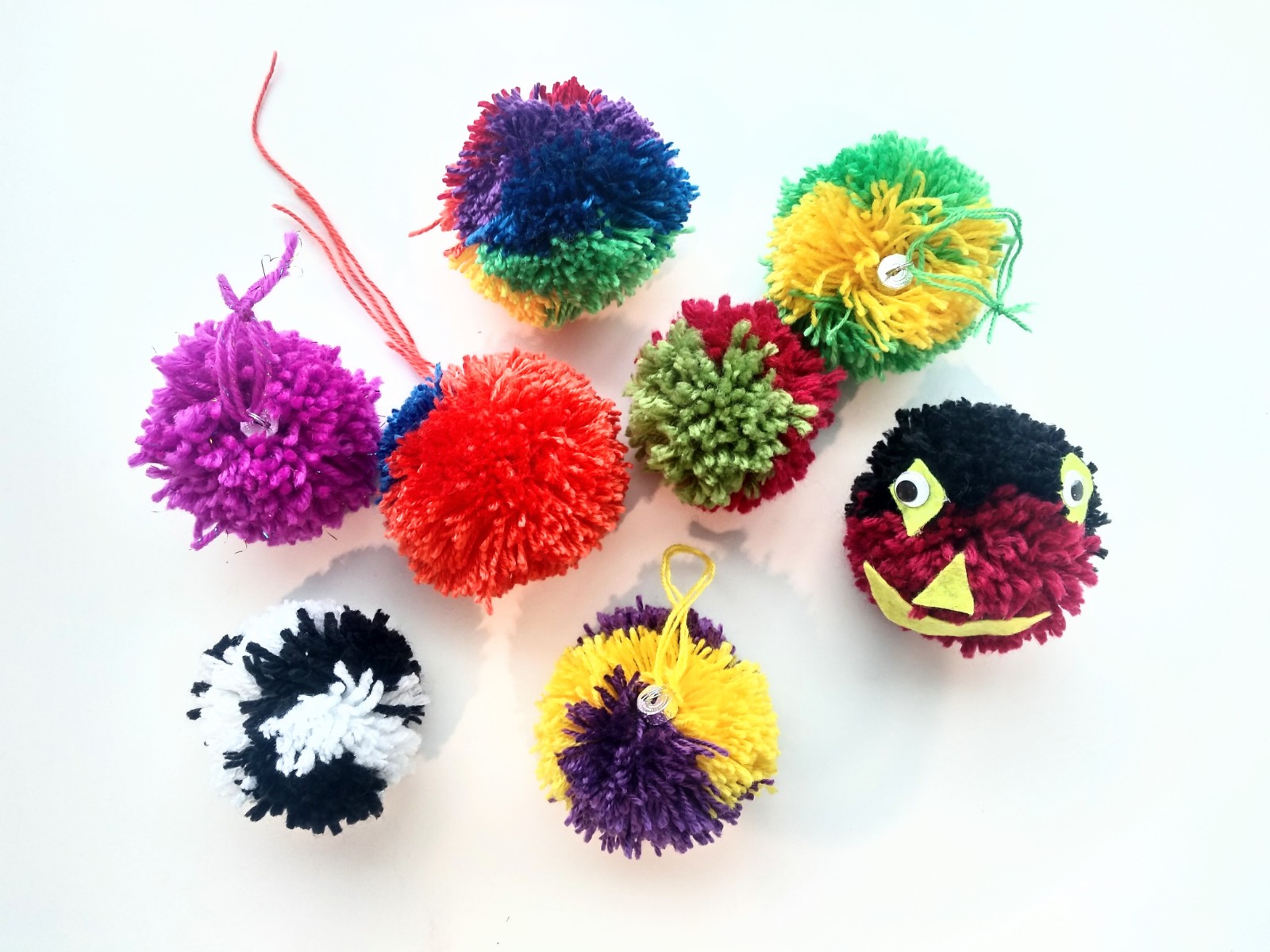 8 yarn pompoms that also have ornament tops on most of them.