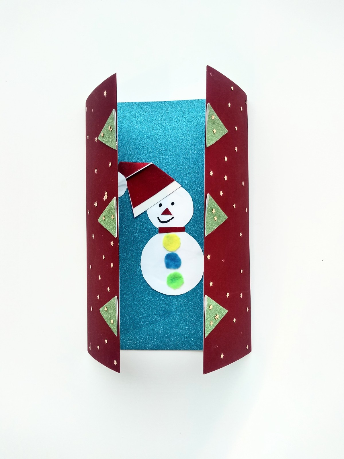 A two panel holiday card. The front is red with green triangles that open up to a snowman in the center of the inside card.