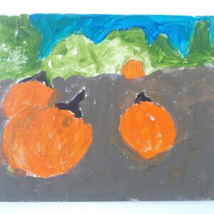 Three pumpkins in an orchard with green trees in the back.