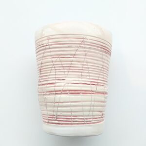 A ceramic pot with red scored horizontal lines across it.