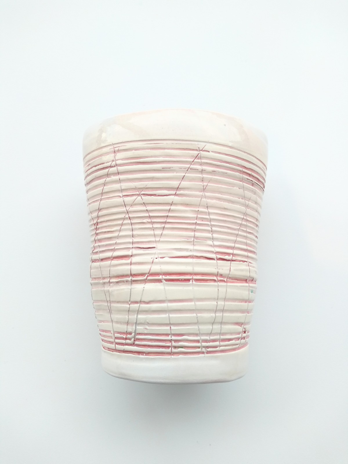 A ceramic pot with red scored horizontal lines across it.