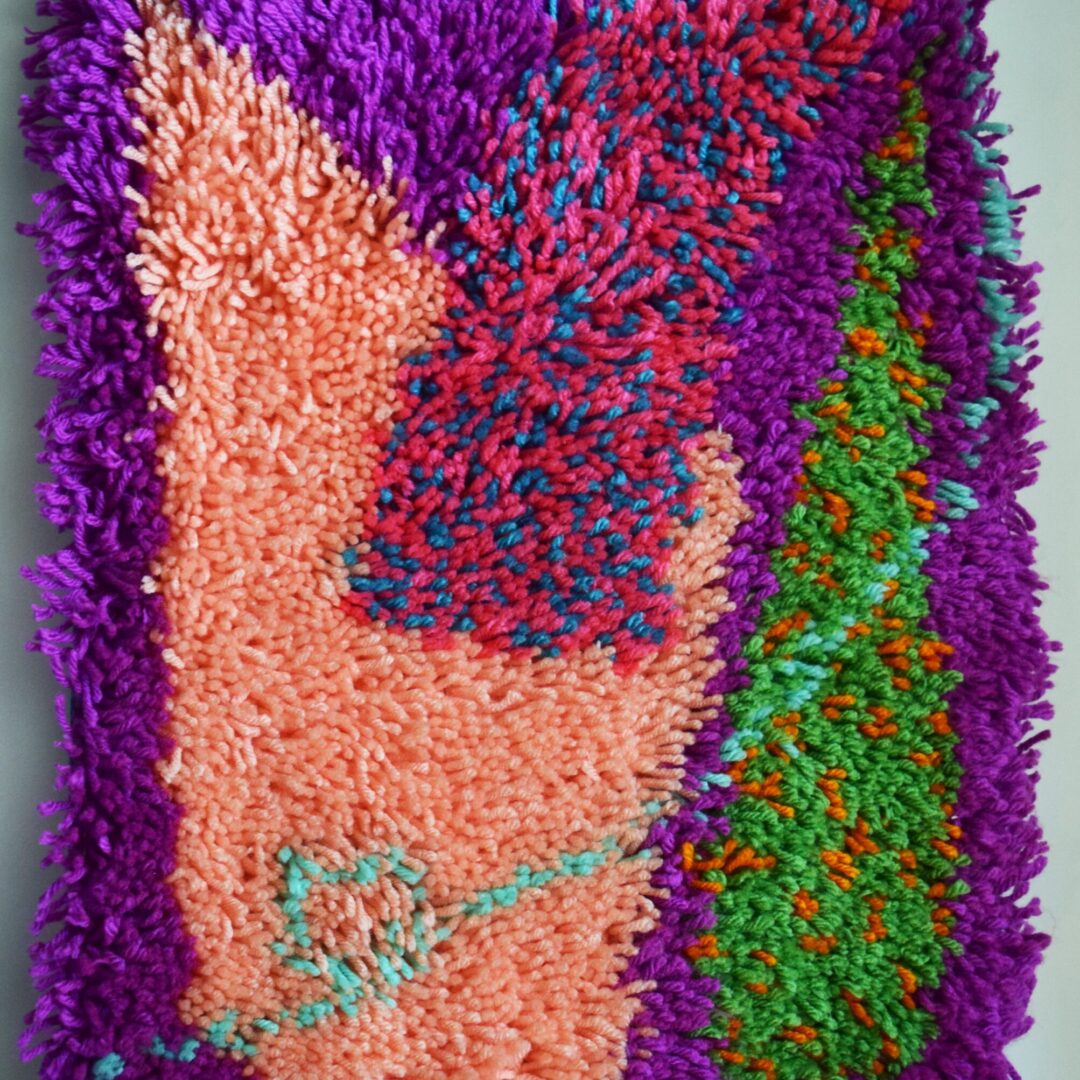 Rectangular yarn piece with colourful geometic shapes.