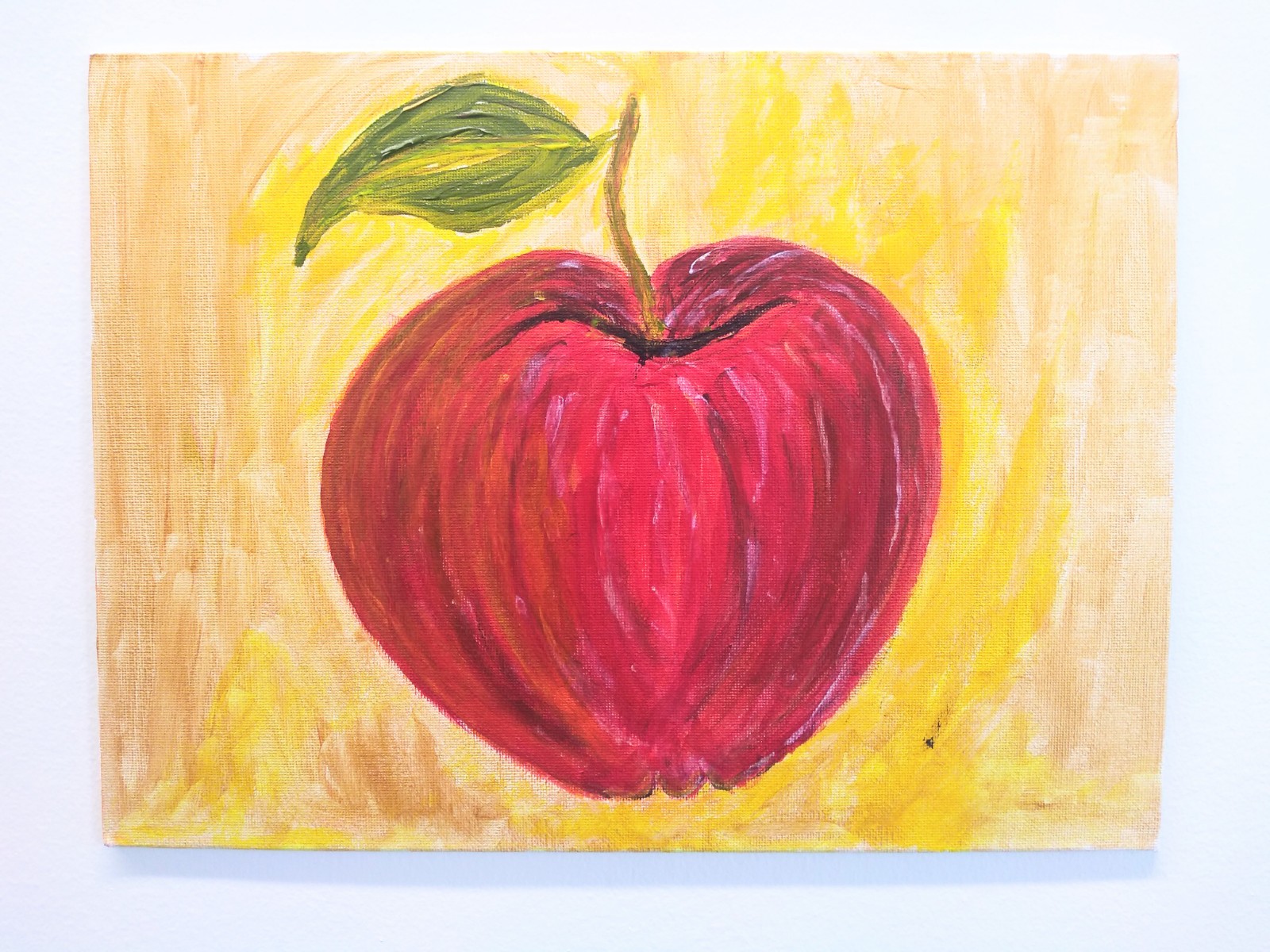 A textured apple with green leaf stem with yellow background.