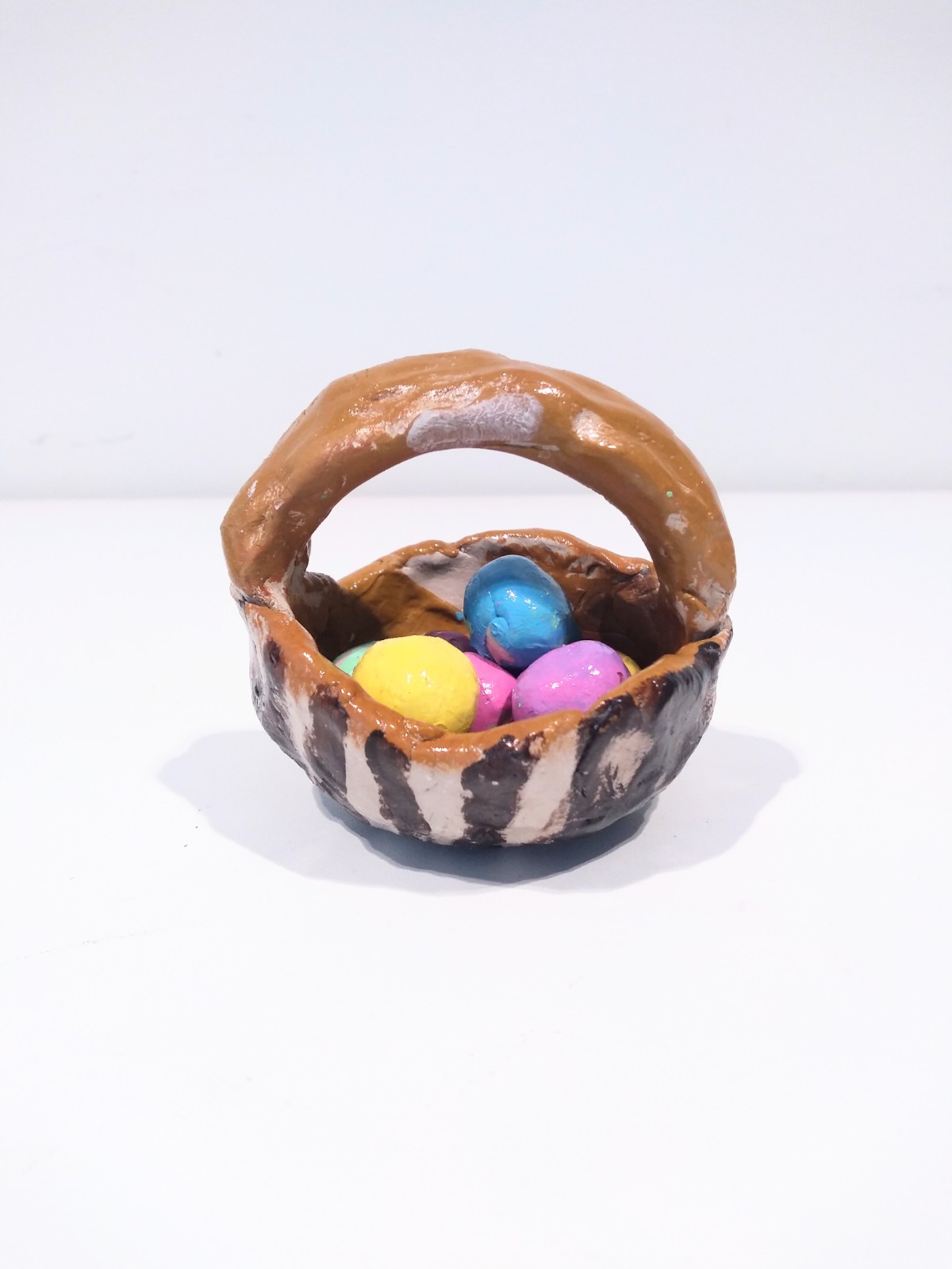 Colourful easter eggs in a brown stripe basket.