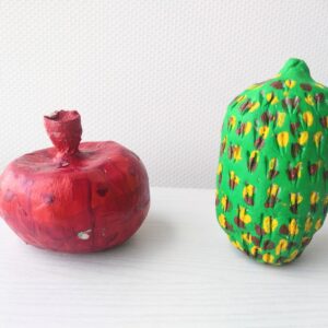Two pieces of fruit, one red pomegranate and oval green fruit with yellow and brown spots.