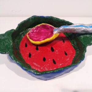 Green dish border around watermelon center with two handles with a spoon.