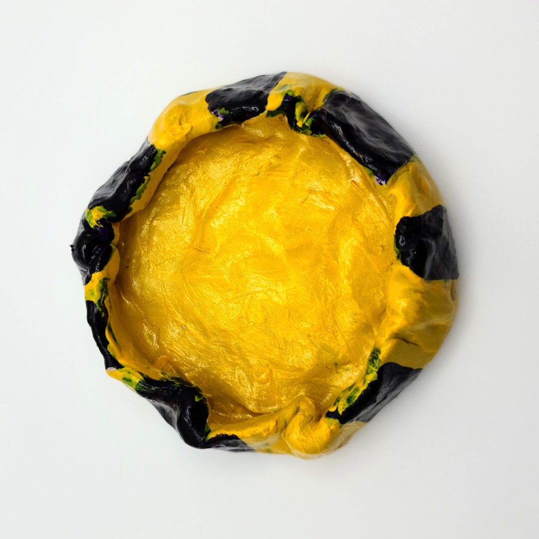 Top view of clay bowl painted in yellow and dark blue stripes.