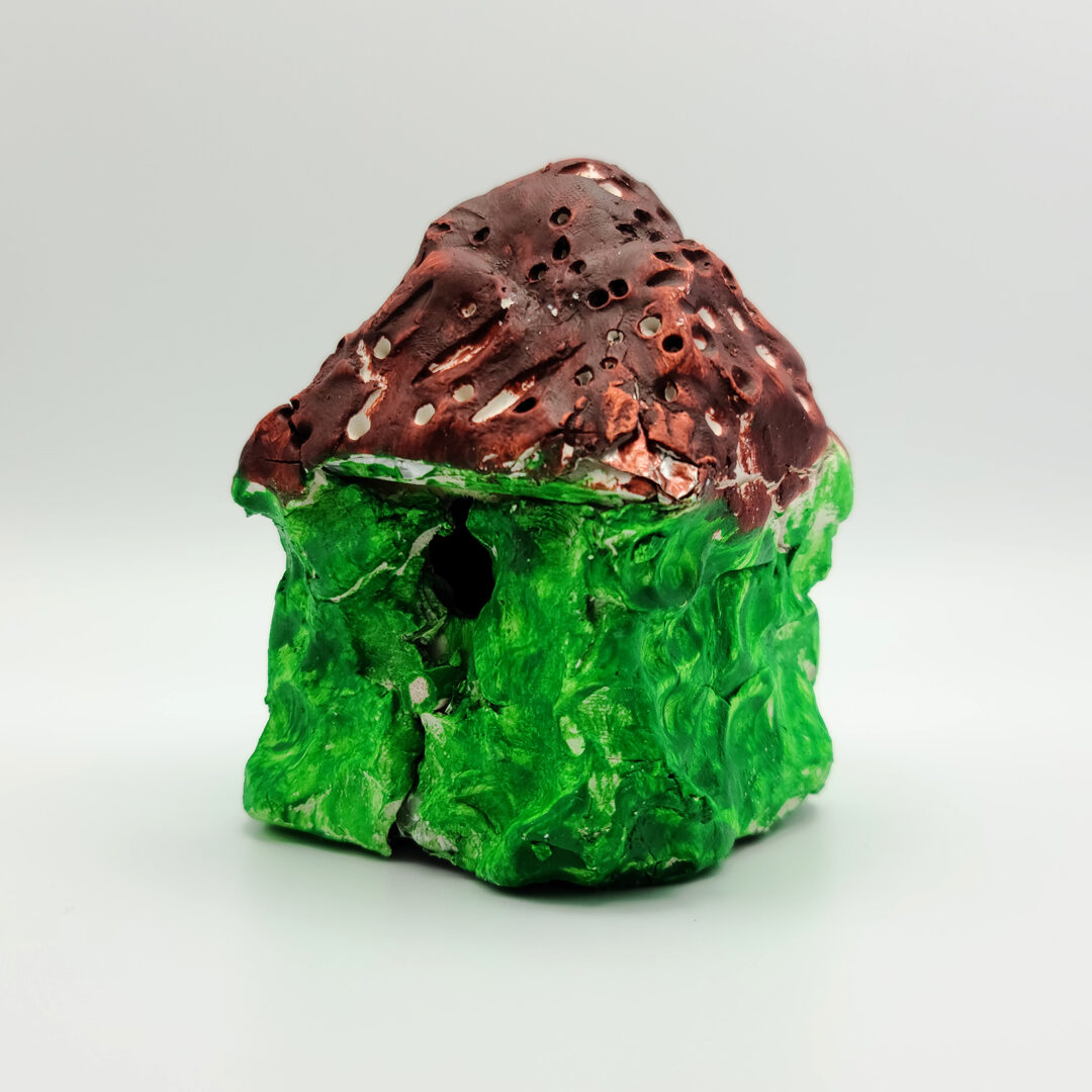 Clay sculpture of a house with a green base and brown roof.