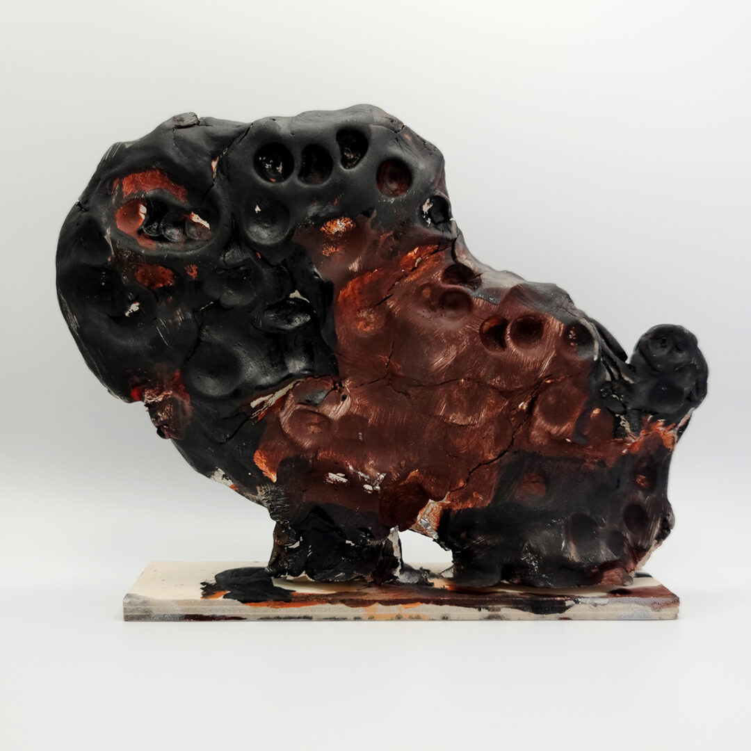Clay sculpture of a buffalo shape, painted in black and brown.