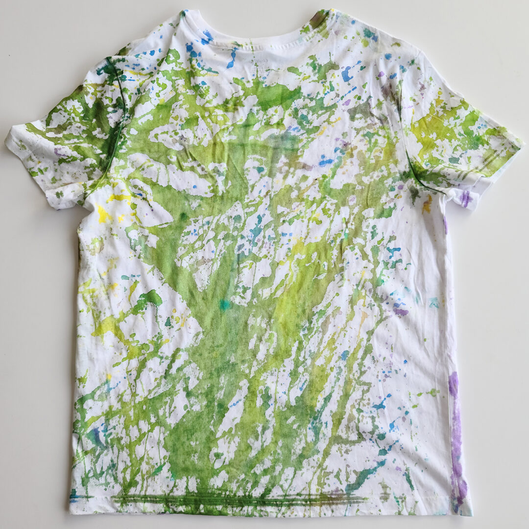 White t-shirt tie dyed with purple and green splatters.