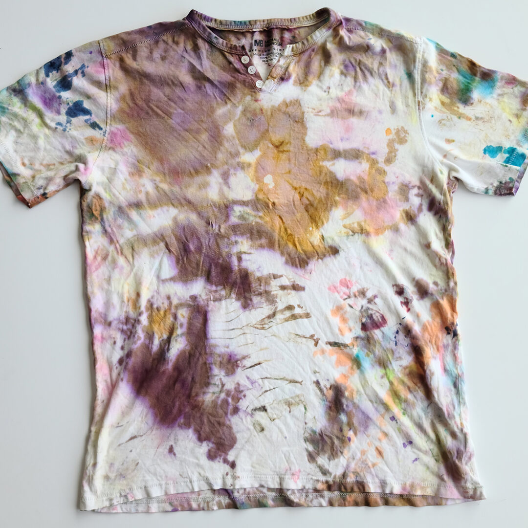 White t-shirt tie dyed with splatters of orange, red and purple.