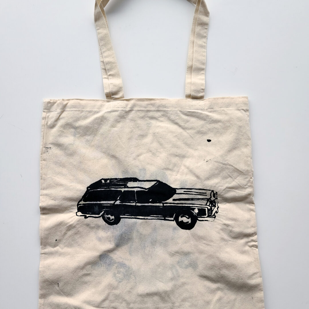 Tote bag screenprinted with illustration of a station wagon in black.