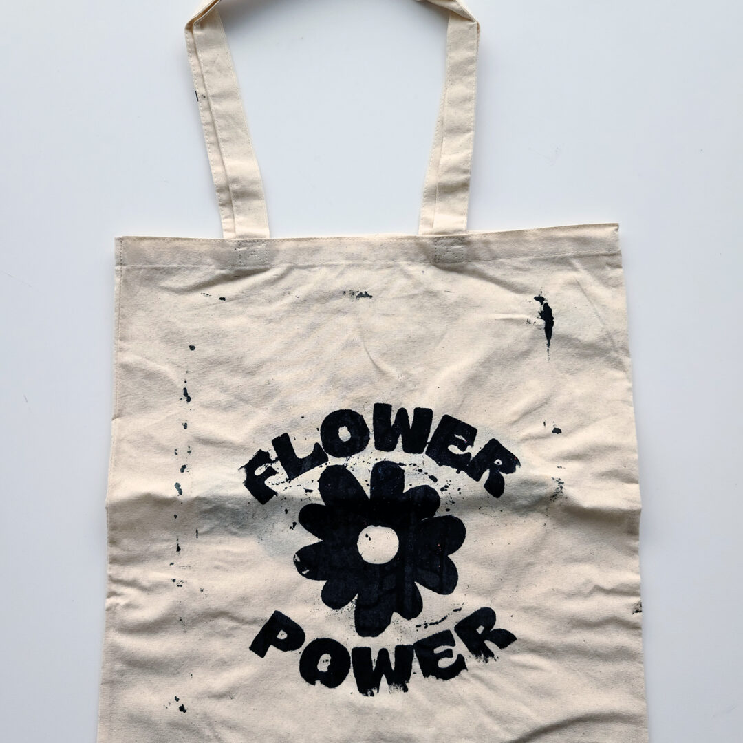 Tote bag screenprinted with illustration of a flower and the words 'Flower Power' in black.