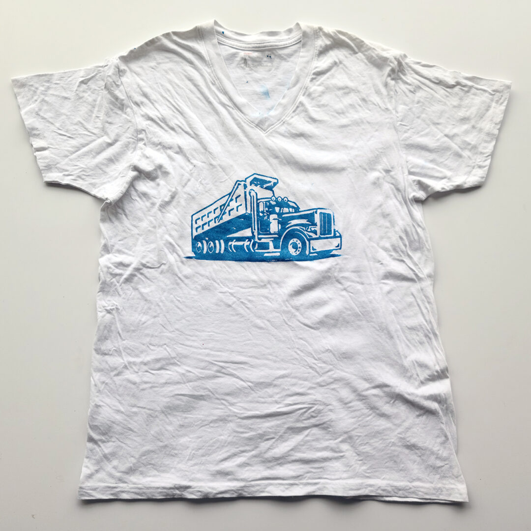 A white t shirt screenprinted with an illustration of a truck in blue.