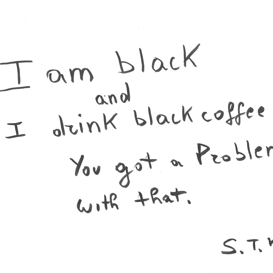 Black marker writing: 'I am black and I drink coffee. You got a problem with that.' Signed S.T.K.